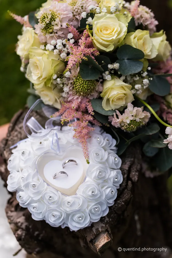 Alliances de mariage posées dans un écrin de roses blanches avec bouquet de mariée roses blanches
